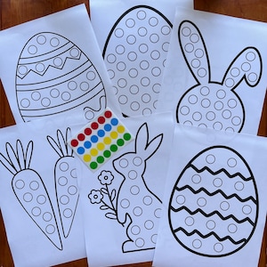 May include: Five printable Easter-themed dot-to-dot activity sheets featuring a bunny, carrots, and eggs. Each sheet has a black outline of the image with circles for children to connect with dot stickers.