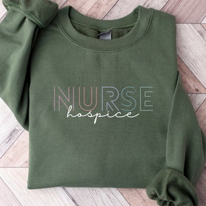 May include: A green sweatshirt with the text "NURSE hospice" in rainbow colors.