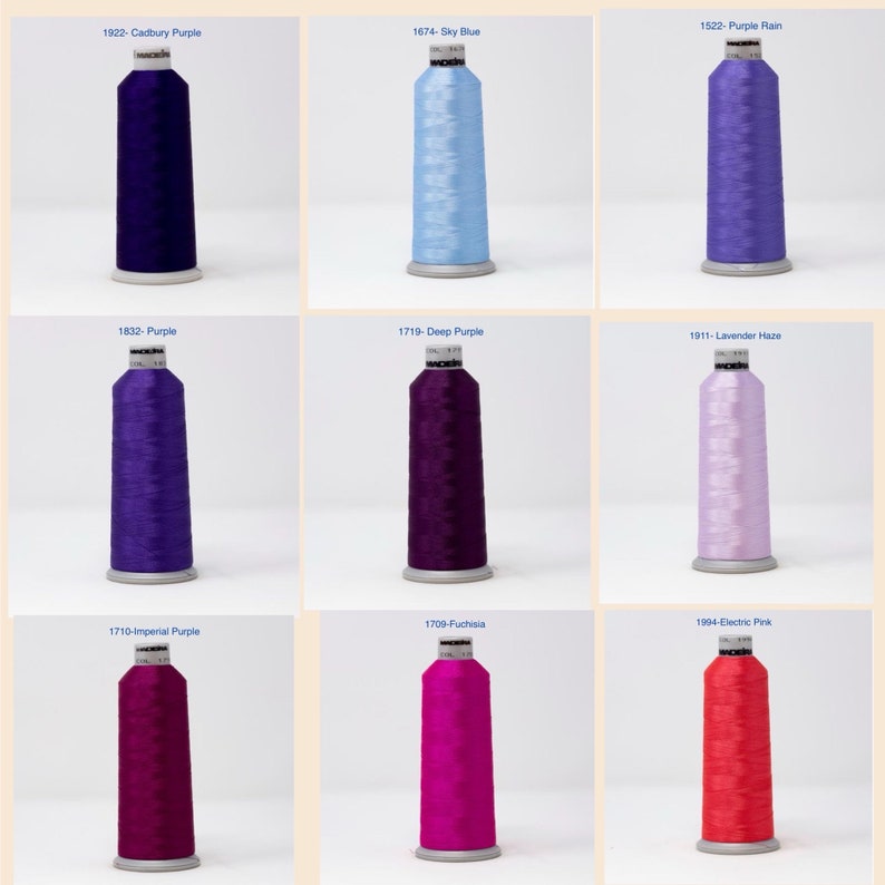 May include: Nine spools of embroidery thread in various shades of purple, pink, and blue. The spools are labeled with their corresponding color names and numbers.