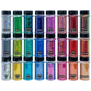 May include: Thirty-six small glass jars filled with iridescent glitter. Each jar has a black lid and a label with a different name, such as "Stardust", "Jade", "Northern Lights", and "Nebula".