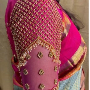 Puede incluir: Una manga de blusa bordada en rosa y dorado con abalorios intrincados y una tela de red delicada. La manga presenta un patrón geométrico con un detalle de flecos en la parte inferior.