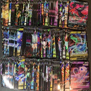 May include: A large collection of Pokémon trading cards, featuring various characters and designs. The cards have colorful holographic foil accents and Japanese text. The cards are stacked together, showcasing a variety of card types and artwork.