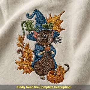 Könnte beinhalten: Ein cremefarbener Stoff mit einer Stickerei einer braunen Maus, die einen blauen Hexenhut und Umhang trägt und einen kleinen orangefarbenen Kürbis hält. Die Maus ist von goldenen Herbstblättern und einem Kürbis umgeben. Text: Kindly Read the Complete Description!