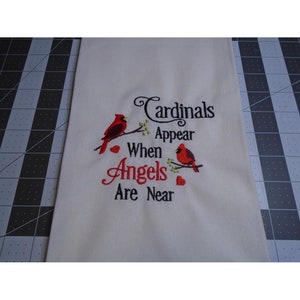May include: White kitchen towel with red cardinals embroidered on a branch with green leaves. The text reads "Cardinals Appear When Angels Are Near".