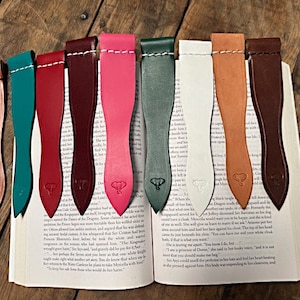 May include: A set of ten leather bookmarks in various colors, including brown, red, pink, green, and white. Each bookmark features a small elephant design and a pointed tip.
