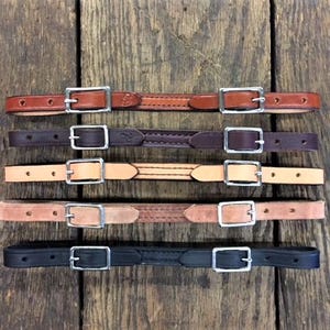 May include: Five leather straps with silver buckles. The straps are in different colors: brown, dark brown, light brown, tan, and black.