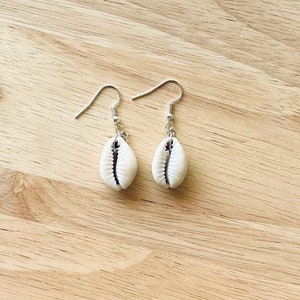 May include: A pair of silver earrings with white cowrie shell charms.