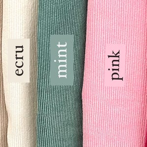 May include: Close-up of four fabric swatches in different colors: ecru, mint, pink, and red. The swatches are arranged side-by-side and have a textured, ribbed surface.