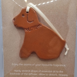 May include: A terracotta-coloured dog-shaped essential oil diffuser with a cream ribbon for hanging. The card reads "ESSENTIAL OIL DIFFUSER". Instructions are printed below the diffuser.