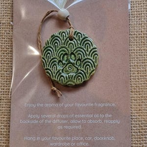 May include: Green ceramic essential oil diffuser with a paw print design. It has a string for hanging and instructions on the back.