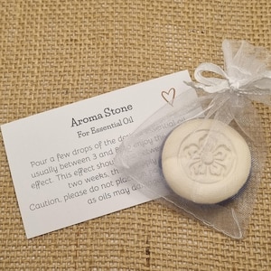 May include: Aroma stone for essential oil, in a white organza bag tied with a ribbon. The round stone has a floral design and is shown with a card detailing usage instructions.