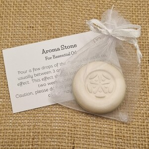 May include: Aroma Stone for essential oils, in a white organza bag with a ribbon tie. The round, off-white stone features an embossed design. A card with instructions is included. Ideal for aromatherapy.