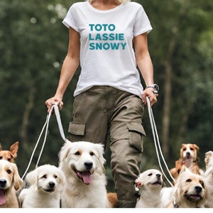 May include: A woman in a white t-shirt with the text "TOTO LASSIE SNOWY" walks with a group of dogs on leashes. The dogs are a mix of breeds, including a golden retriever, a terrier, and a husky.