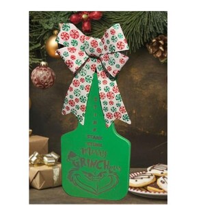 May include: A green Christmas ornament shaped like a tag, with the text "STINK STANK STUNK MERRY GRINCHMAS" and a Grinch face. It has a bow with red and green peppermint candy print. Christmas decor.