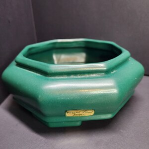May include: A green octagonal ceramic planter with the text "Haeger Floral, Macomb, IL, Made in U.S.A." on the bottom.