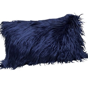 May include: A navy blue faux fur throw pillow. The pillow is made of a soft, fluffy material and has a rectangular shape.