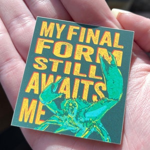 May include: A green crab with yellow claws on a dark green background with the text "MY FINAL FORM STILL AWAITS ME" in yellow letters.