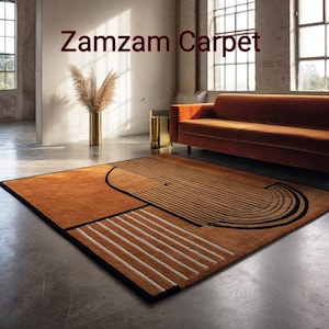 May include: A rectangular area rug featuring a burnt orange base with black and white geometric line patterns, including semi-circular and linear designs. The text "Zamzam Carpet" is visible in the upper portion of the image.
