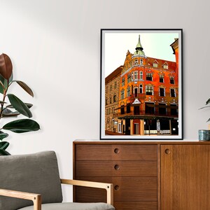 May include: A digital illustration of a red brick building with a green roof and a tower. The building has many windows and is located on a street corner.