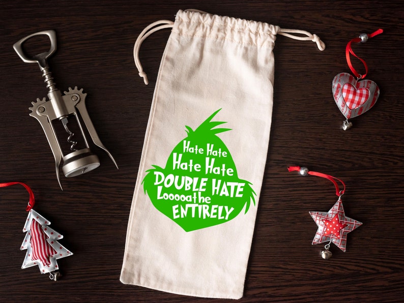 May include: A canvas wine bag with a green graphic and the text "Hate Hate Hate Hate DOUBLE HATE Loooooathe ENTIRELY". A silver corkscrew and Christmas ornaments are also in the image.
