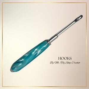 May include: A crochet hook with a teal and white marbled handle and a silver metal shaft. The text "HOOKS By Mr. Toy Shop Crochet" is displayed below the hook.