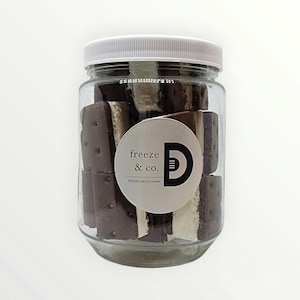 May include: A glass jar filled with freeze-dried ice cream sandwiches. The jar has a white lid and a label that says "freeze & co." and "freeze dried ice cream".