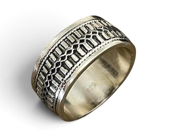 May include: A wide silver band ring featuring a detailed embossed pattern of vertical rectangular bars and a central wavy line. The interior of the band is smooth and clearly stamped with the hallmark 925, indicating sterling silver composition.