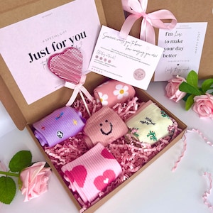 May include: A gift box filled with pink and white patterned socks, a pink heart-shaped lollipop, and a card that says "Someone wants you to know how amazing you are!"  The box is decorated with pink tissue paper and a pink ribbon.