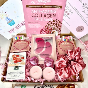 May include: A pink and brown gift box filled with various items, including a face mask, eye masks, a hair scrunchie, chocolate, candles, and a card that says "Happy Birthday".