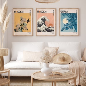 May include: Three framed prints of Japanese woodblock prints. The prints are in a minimalist style with a white background and black text. The prints feature a wave, a flower, and a tree. The text on the prints reads "KATSUSHIKA HOKUSAI" and "葛飾北斎".