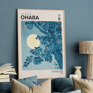 May include: A framed print of a Japanese woodblock print depicting a cherry blossom branch with a full moon in the background. The print is titled "Blossoming Cherry on a Moonlit Night (1943)" and is signed "Koson Ohara".