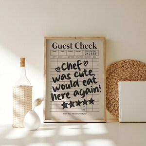 May include: A framed black and white guest check with a handwritten message that reads "Chef was cute, would eat here again!" with five stars below the message. The check number is 241835.