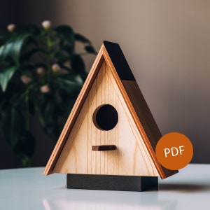 May include: A wooden birdhouse with a triangular roof and a black base. The birdhouse has a round entrance hole and a small perch. The word "PDF" is printed on a brown circle in the lower right corner of the image.