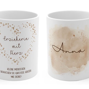 May include: White ceramic mug with a brown heart design and the text "Erzieherin mit Herz" and "Kleine Menschen brauchen so grosse Herzen wie deins!" on one side. The other side of the mug has a brown watercolor design with the name "Anna" written in cursive.