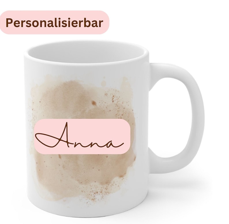May include: White ceramic mug with a brown watercolor design and a pink rectangle with the name "Anna" written in brown cursive.