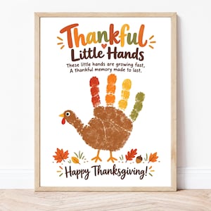 May include: A framed print featuring the text Thankful Little Hands, These little hands are growing fast, A thankful memory made to last, and Happy Thanksgiving. A handprint turkey graphic with colorful fingers sits in the center.