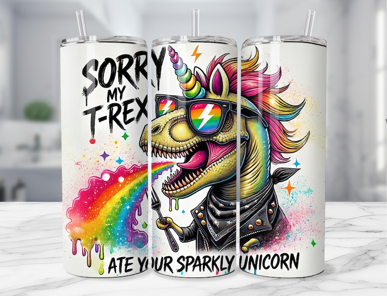 Puede incluir: Un vaso blanco con un gr&aacute;fico colorido de un unicornio que est&aacute; siendo comido por un T-Rex. El T-Rex lleva gafas de sol y una chaqueta de cuero. El texto en el vaso dice "Lo siento, mi T-Rex se comi&oacute; tu unicornio brillante".