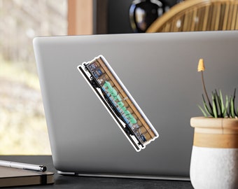 May include: A sticker featuring a stylized illustration of a train car with graffiti art. The graffiti reads "DREAM" in green and white against a brown background. The sticker is placed on a laptop.