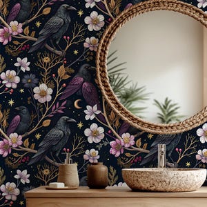May include: A bathroom with a dark floral wallpaper featuring crows, flowers, and moons. A round mirror hangs above a wooden vanity with a stone sink. Woven baskets and a towel complete the decor, creating a nature-inspired aesthetic.