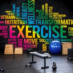 May include: A gym with a black wall featuring a colorful word cloud with the word "EXERCISE" in the center. The word cloud includes words related to fitness, health, and wellness. The gym has a bench, weights, a medicine ball, and other exercise equipment.