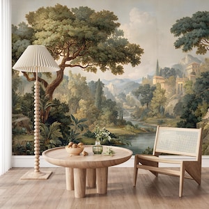 Puede incluir: Escena de habitación con un mural de paisaje, una mesa de centro redonda de madera, una silla con respaldo de mimbre y una lámpara de pie con pantalla plisada. El mural representa un paisaje clásico con árboles, agua y edificios. Los muebles son de madera clara.