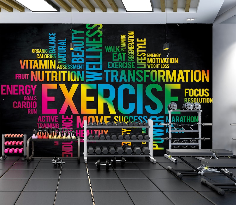 May include: A black chalkboard wall with a colorful word cloud centered around the word "EXERCISE". The word cloud includes words related to fitness, health, and wellness. The wall is in a gym setting with weight racks and other fitness equipment.