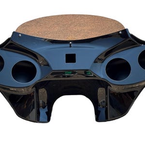 Puede incluir: Carenado de motocicleta negro con cuatro recortes para altavoces y un parabrisas marrón.