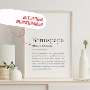 Könnte beinhalten: Ein gerahmter Druck mit dem Wort "Bonuspapa" in schwarzer Schrift, zusammen mit einer Definition und einer Botschaft über einen Bonusvater. Oben links steht "MIT DEINEM WUNSCHNAMEN" in einer roten Sprechblase.