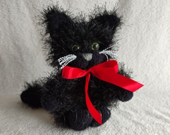 May include: A black knitted plush cat toy with a red bow. The cat has green eyes and white whiskers.