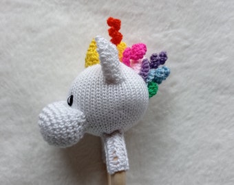 Puede incluir: Sonajero de unicornio blanco de crochet con una melena arcoíris y un mango de madera.