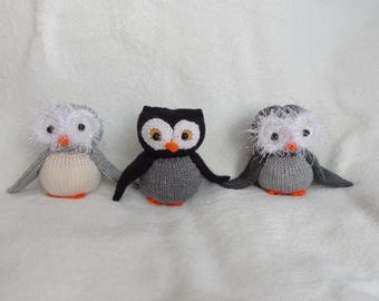 May include: Three knitted owl toys. One is white with black eyes, one is gray with black eyes and a black beak, and one is gray with black eyes and a black beak. All three owls have orange beaks.