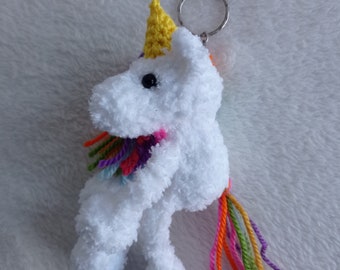 Puede incluir: Llavero de unicornio de crochet blanco con un cuerno amarillo, una cola de hilo arcoíris y un anillo de llave plateado.
