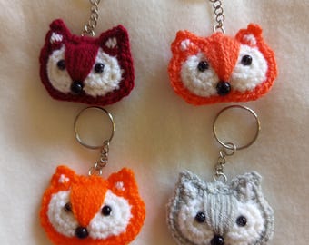 May include: Four handmade fox keychains. The keychains are crocheted with white, orange, red, and gray yarn. Each fox has black bead eyes and a silver keyring.