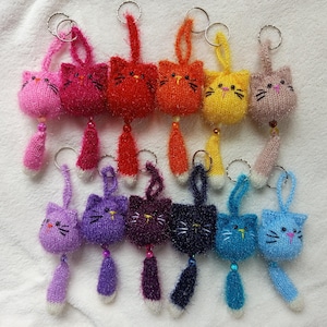 Pode incluir: Um conjunto de 10 chaveiros de gato de malha coloridos com caudas fofinhas. Cada chaveiro apresenta uma cor diferente e um rosto de gato bonito.